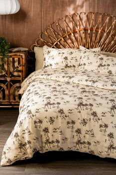 A beautiful bed with a wicker headboard and pretty floral bedding, styled next to a wooden bedside table and wall light