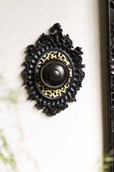 A wall bell that is black and leopard print. 