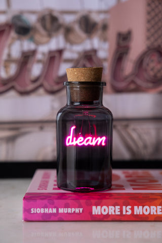 A neon light in a bottle that says "dream".