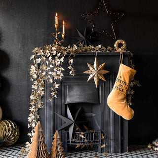 Black fireplace styled with trailing gold ivy garland, star decorations and a christmas stocking.