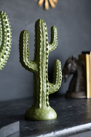 An ornament of a cactus styled on a black sideboard. 