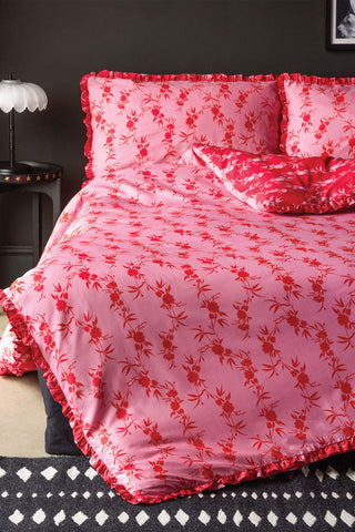 Red and pink floral bedding on a made bed. 