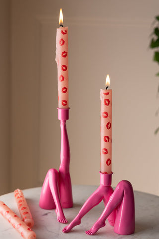 Pink candle holders shaped as kicking legs with pink taper candles in them.