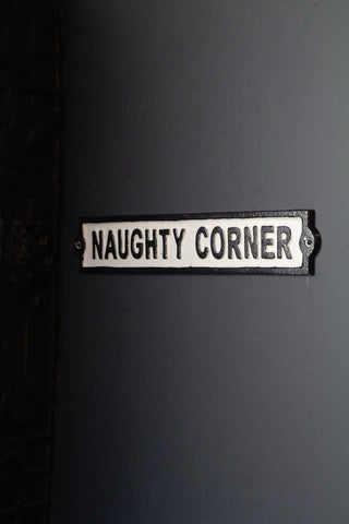 A metal sign that say Naughty Corner on it. 