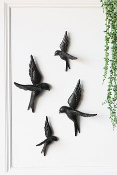 A set of 4 black birds wall decor on a white wall. 