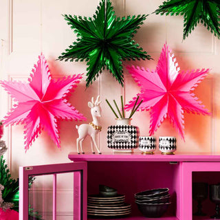 A cabinet styled for a colourful Christmas party with hot pink and emerald green stars