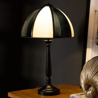 A spot print mushroom lamp displayed on a table with some books.