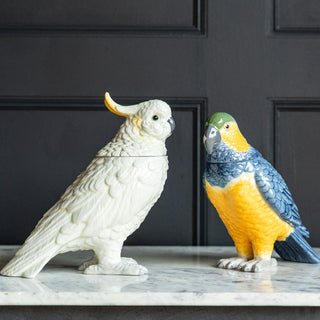 The Ceramic Cockatoo and Parrot Storage Jars displayed together on a marble table in front of a black panelled wall.