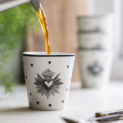 Three colourful glass mugs styled on a wooden serving board on a kitchen worktop.