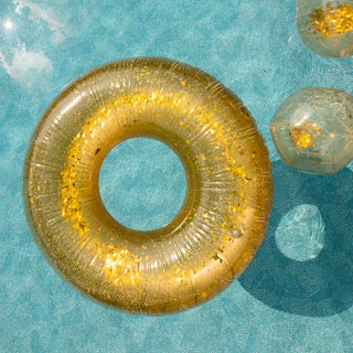 Lifestyle image of the Rockett St George Disco Gold Inflatable Pool Ring and Beach Balls shown floating on the surface of a swimming pool in the sunshine.  