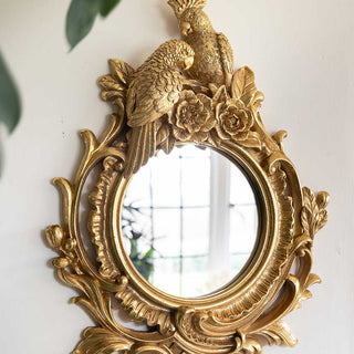 beautiful gold frame mirror with two parrots at the top.