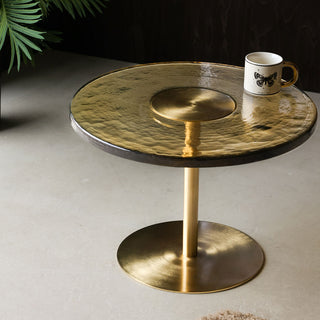 The Amber Glass Coffee Table styled with a mug on and a plant in the background.