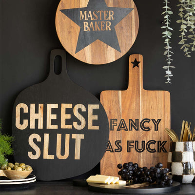 Various serving boards styled with food and greenery in front of a black wall.