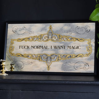 The Fuck Normal, I Want Magic Mirror displayed leaning against the wall on a black sideboard, styled with a plant and wax-covered candlesticks.
