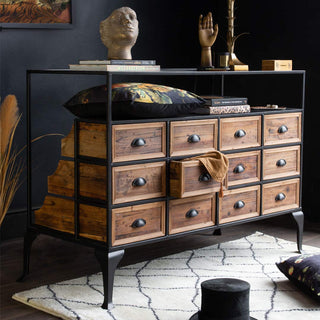 Image of Rockett St George Haberdashery 12 Drawer Shop Counter With Glass Top styled with various home accessories including cushions, rug, ornaments and faux plant stems. 