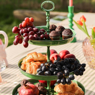 The Fresh Green Large Enamel Tiered Serving Tower displayed with fruit and cakes, styled on an outdoor tablescape.
