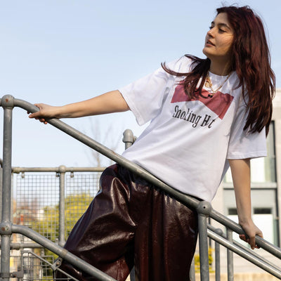 A model wearing a graphic tee posting outside on some stairs.