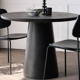 The Round Indoor Dining Table In Cocoa styled with chair, bowls, a candle and candlestick holder.