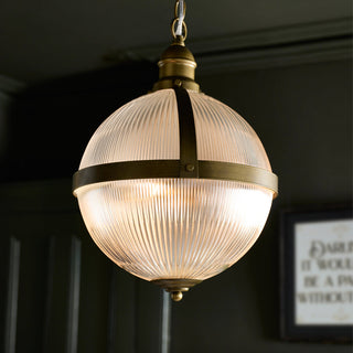 Lifestyle image of the Outdoor Vintage Orb Light hanging illuminated in a dark wall. There is an art print on the wall in the background.