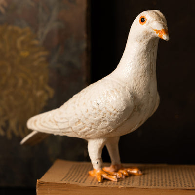 a quirky dove ornament styled on a book, in front of a dark background.