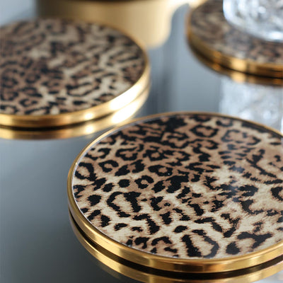 The Set Of 4 Leopard Print Coasters displayed on a table, with a drinking glass.
