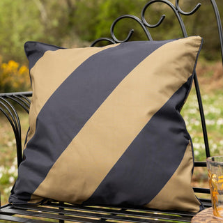The Black & Green Stripe Outdoor Cushion displayed on a black metal bench in a garden.