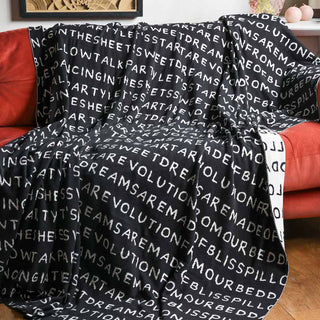 The Black Lyric Throw displayed draped over a sofa with decorative home accessories in the background.