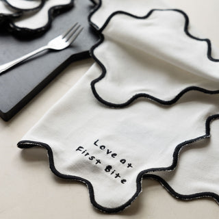 The Set of 4 Black & White First Bite Napkins displayed on a table with a serving board and cutlery.