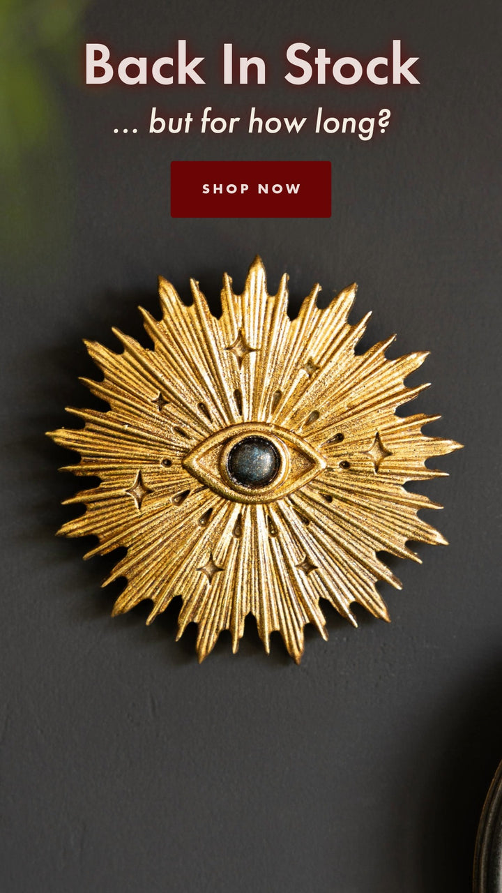 A gold starburst wall ornament featuring a mystic eye in the centre of the star 