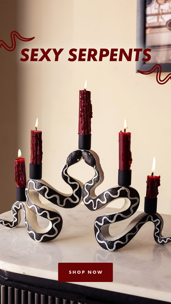 A candle holder designed to look like two snakes converging together, with five red dinner candles 