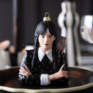 Decorative wednesday figurine of a person with braided hair and black outfit on a dark surface.