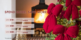 Promotional graphic with Christmas tree, fireplace, and red bows, featuring savings text.