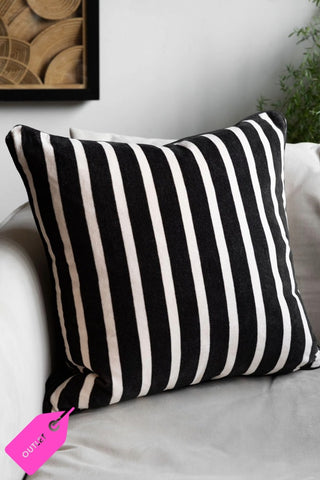 The Monochrome Striped Velvet Cushion Cover shown with a pad on a white chair.