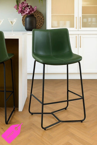 Set of two green bar stools with black legs in a kitchen setting.