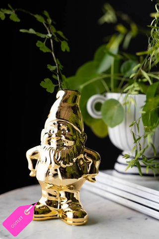 The Gold Gnome Single Stem Vase / Candlestick Holder styled with greenery inside, with magazines and a planter in the background.