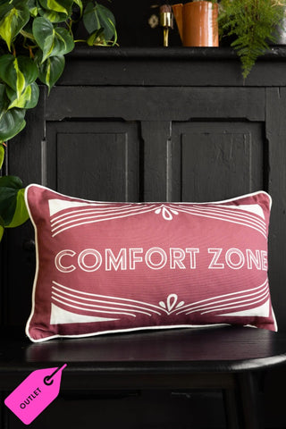 The Heritage Comfort Zone Cushion In Red styled on a dark bench, with a black cabinet and accessories in the background