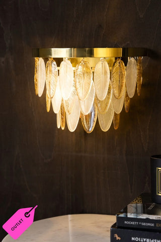 The Stunning Art Deco Glass Feather Wall Light displayed switched on against a dark wood wall.