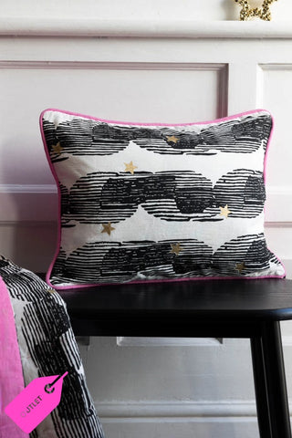 Image of the Hot Pink & Gold Star Print Reversible Cushion styled on a black bench against a white panelled backdrop.