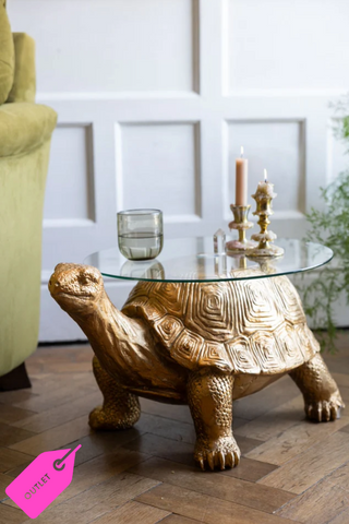 Image of the Gold Tortoise Side Table on a wooden floor with a glass and candlesticks on the surface.