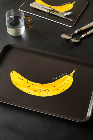 Lifestyle image of the Top Banana Tray, styled with the matching design placemat, cutlery and glassware.