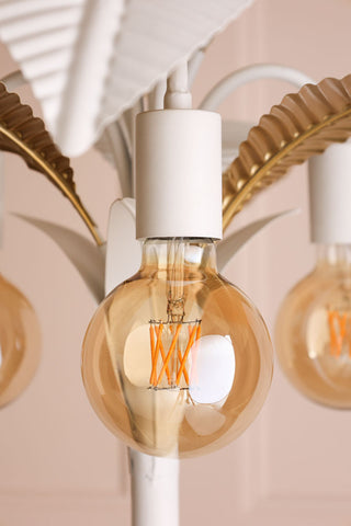 Lifestyle image of the Globe E27 6W Amber LED Light Bulb styled on a white lamp. 