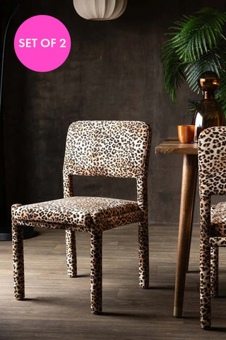 The Set Of 2 Signature Leopard Velvet Dining Chairs styled next to a table with set of 2 badge. 