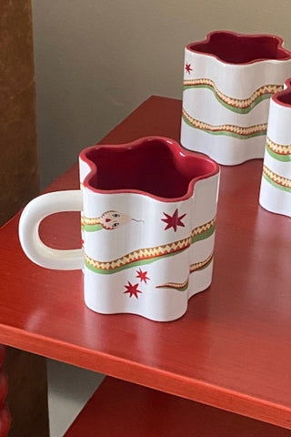 Star Shaped Mugs with Snake Print Detail on a red surface