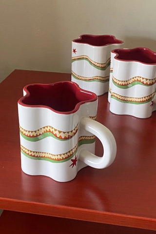 Set of 3 Star Shaped Mugs with Snake Print Detail on a red surface