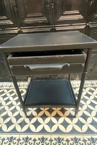 The Metal Industrial Bedside Table on a geometric floor with the drawer slightly open
