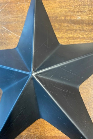 Close up image of a star from Image of the large star from the Set Of 3 Black Metal Stars on a wooden background