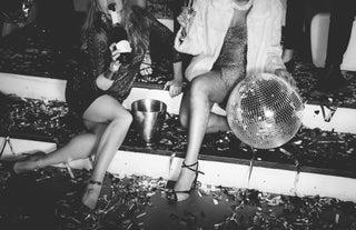 Image of two girls sitting on a step surrounded by streamers and a disco ball.
