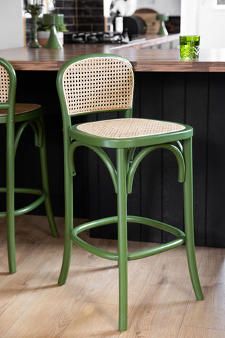 Two of the Chez Pitou Wood & Woven Cane Bar Stool in Green styled ina  kitchen next to a breakfast bar.