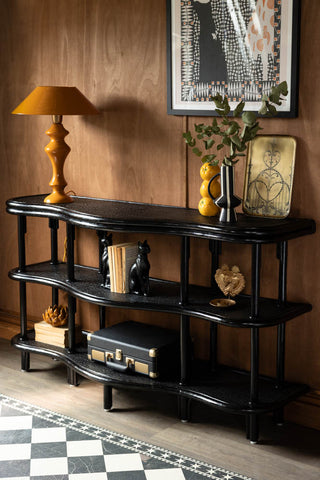 The Vintage-Inspired Black Rattan Console Table styled in front of a wall, with various accessories on it.