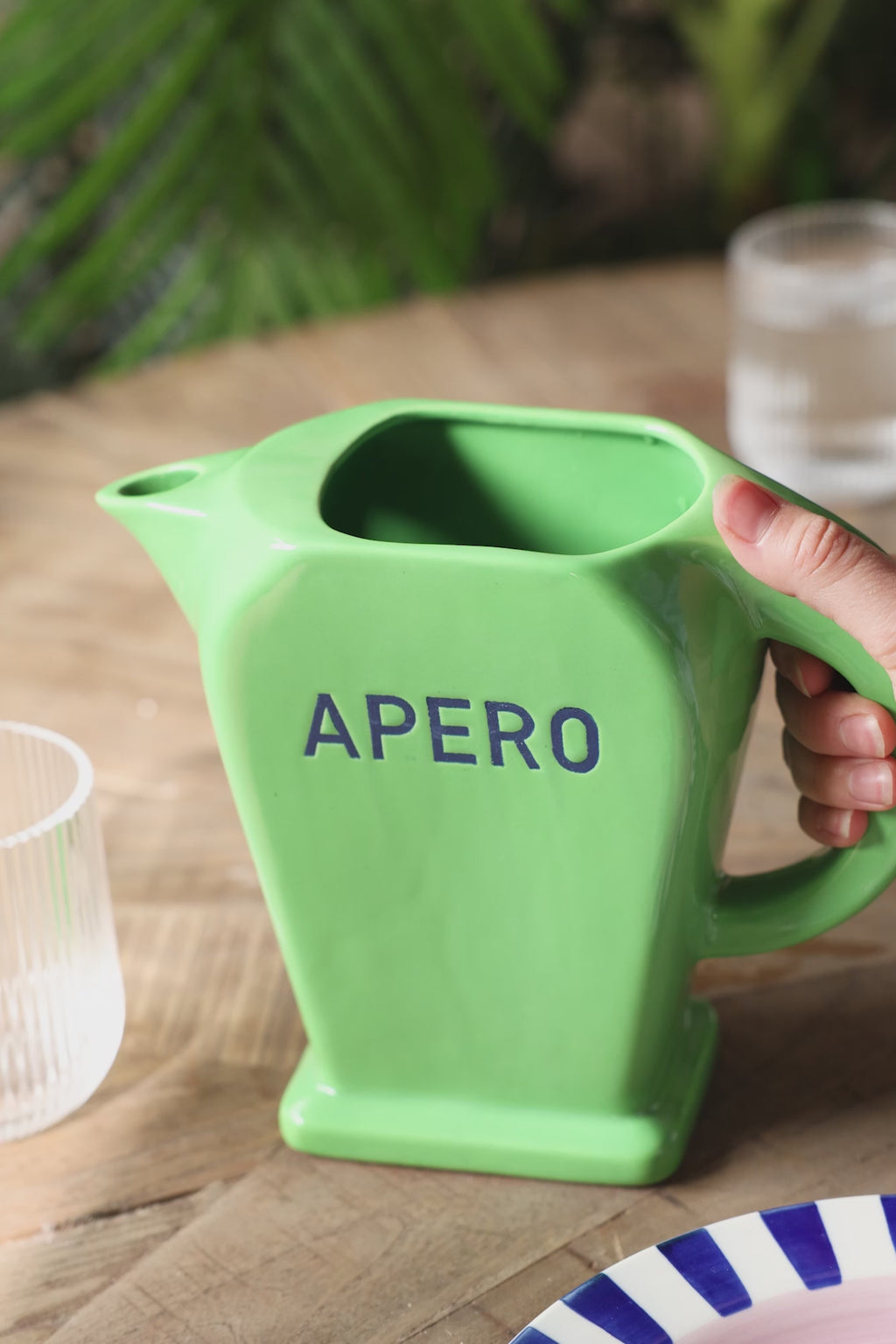 A video of someone pouring water from the Stylish Green Apero Water Jug into a drinking glass on a table.